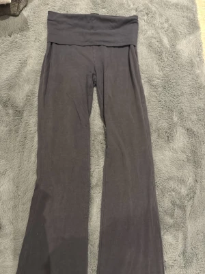 Yogapants - Säljer ett par mörkgrå mjukisbyxor med bred linning och bootcut-ben. Byxorna är i mjukt och stretchigt material, perfekta för chill dagar eller när du vill vara extra bekväm. Passar dig som gillar en avslappnad och trendig stil.