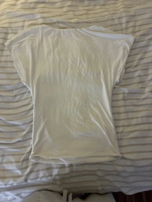 Vit kortärmad t-shirt - En enkel vit t-shirt med korta ärmar och rund hals. T-shirten sitter tajt nertill och lösare uppe och är tillverkad i ett mjukt material, perfekt för en avslappnad stil. Passar till det mesta och är ett måste i garderoben.