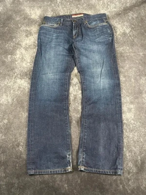 Blå Tommy Hilfiger vintagejeans för herrar i storlek W32 L32 - W & L är baserade på måtten. Snygg vintageinspirerad modell med sliten tvätt och bekväm bomullsdenim.  Skick: 9,5/10  Midja: 43 cm Benslut: 20 cm Lår: 30 cm Totallängd: 103 cm Måtten finns även på bilderna  Skickas inom ett dygn Spara på priset och frakten genom att sätta ihop ett paket! 5-105