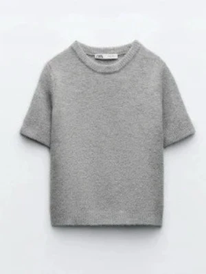 Grå stickad topp med kort ärm - Mysig grå stickad topp med rund halsringning och korta ärmar. Perfekt för lager på lager och enkel att matcha med både jeans och kjol. Tidlös design som passar till många olika stilar.