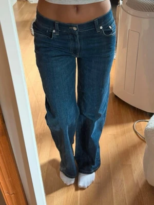 Mörkblå raka jeans - Säljer ett par mörkblå jeans med rak passform och klassisk femficksdesign. Jeansen har normal midja och stängs med knapp och dragkedja. Materialet är denim i bomull och de har en tidlös look som passar till det mesta.