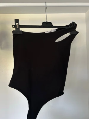 Svart asymmetrisk body från NA-KD - Snygg svart body från NA-KD med asymmetrisk design! Endast använd en gång!