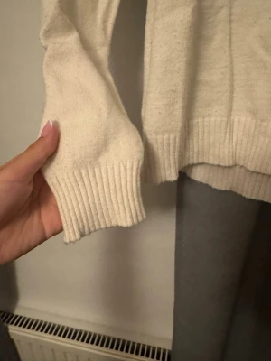 Krämvit stickad tröja från Vila - Mysig krämvit stickad tröja från Vila med rund halsringning och ribbade muddar vid ärmslut och nederkant. Enkel att matcha med olika outfits.