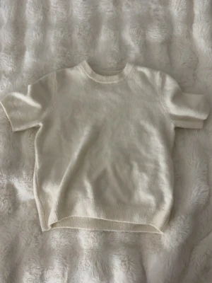 Krämvit stickad kortärmad tröja - Stickad tröja med korta ärmar från H&M. Mycket bra skick och andvänd  max 4-5 gånger💓Swep för bild på hur den ser ut på