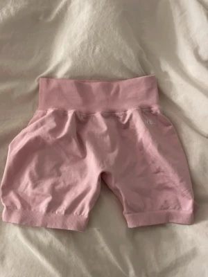 Rosa shorts från AYBL med hög midja - Säljer ett par ljusrosa shorts från AYBL med bred ribbad hög midja. De är tillverkade i mjukt bomullsmaterial och har en relaxed passform. Perfekta för träning eller chill dagar. Är helt nya har inte använt de❤️