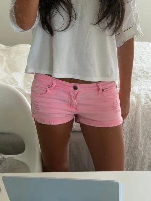Rosa lågmidjade jeansshorts  - Superfina och färgglada rosa shorts i denimliknande material från märket Madonna. Shortsen har snygga slitna detaljer fram, uppvikta benslut och kontrasterande sömmar i en starkare rosa nyans. Klassisk 5-fickorsmodell som är jättesnygg till sommaren! Storlek M på lappen, midjemåttet är ungefär 36cm rakt över så jag skulle säga att det är mer som ett S (alla mått finns i bilderna). ⭐️