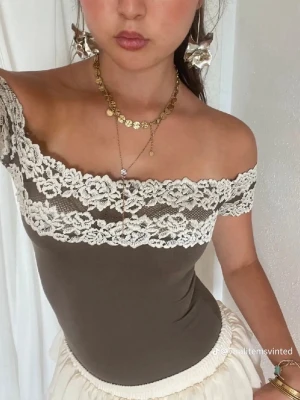 Brun off shoulder body med spets intimissimi - Supersnygg brun body från intimissimi med off shoulder-modell och breda vita spetsdetaljer upptill. Stretchigt material som sitter tajt och framhäver figuren. Perfekt att styla med kjol eller jeans för en trendig look.