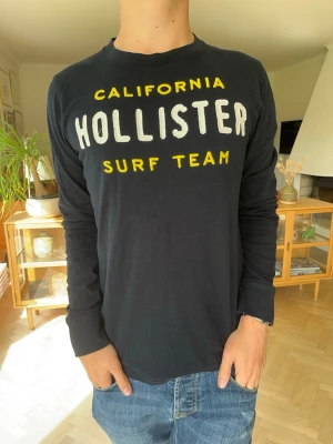 Hollister långärmad tröja vintage herr blå - Snygg svart långärmad Hollister-tröja med klassiskt California Surf Team-tryck i gulvitt. Enkel och stilren modell som passar perfekt till jeans eller chinos. Fint skick och redo att användas! 🌴  #Hollister #HollisterCo #California #SurfTeam #LongSleeve #Långärmad #Streetwear #Casual #Y2K #Preppy #VintageStyle #Americana #Vinted