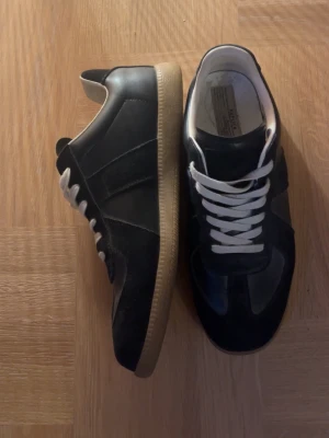 Svarta sneakers Maison Margiela - Säljer dom här svarta maison magielas då dom inte använts så mycket av mig. Dom är i bra skick det ändå är att det är lite slitet i inner sulan. Bara att höra av sig om du funderar på något!