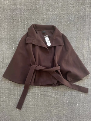 Brun jacka - Säljer en fin jacka från Gina Tricot i storlek M/L. Men den passar också mig som i vanliga fall har storlek xs/s, men det beror lite på hur man vill att den ska sitta. Den är helt ny med prislapp! Modellen heter belt cape jacket och nypriset är 499:-. Skriv vid funderingar!💗