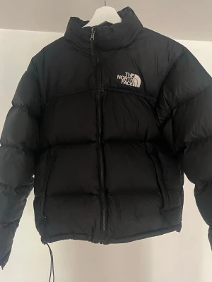 Svart vinterjacka - Säljer min North Face Nuptse 700 1996 puffer jacka då den tyvärr inte är min stil längre. Köpt för 4 år sedan, har tecken på användning såsom enstaka små vita ”repor”, uppljusningar och lite röd penna som kommit på loggan (se bilder) men annars allmänt i fint skick och inget som påverkar dens funktion.