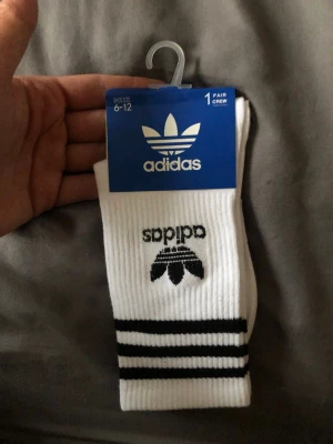 Vita Adidas strumpor med svarta ränder 10st - Klassiska vita Adidas strumpor med svarta ränder och Adidas Trefoil-logga på skaftet. Crew-modell som passar perfekt till sneakers och streetwear. Tillverkade i mjuk och bekväm bomullsblandning.