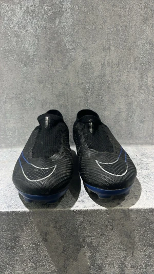 Svarta fotbollsskor med blå detaljer - Snygga svarta Nike fotbollsskor med blå och vita detaljer. Skorna är PRO men är jätte bra kvalitet och köpte dem från Intersport 