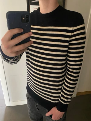 APC sweatshirt  - Säljer en superfint bevarad långärmad tröja (sweatshirt/t-shirt) från det franska kultmärket A.P.C. (Atelier de Production et de Création). 🇫🇷 Den har det ikoniska marinblå- och vitrandiga mönstret och den minimalistiska, eleganta passformen som märket är känt för. Detaljer: • Märke: A.P.C. Rue Madame Paris ✨ • Storlek: Medium (M) 📏 • Färg: Marinblå och vitrandig ⚫️⚪️ • Modell: Klassisk crewneck med långa ärmar och två snygga knappar på vänster axel – en tidlös garderobsklassiker! ⛴️⚓️ • Material: 10