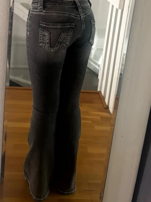 Grå bootcut jeans med vita sömmar - Säljer ett par grå bootcut jeans med markerade vita sömmar och snygga bakfickor. Jeansen har låg midja och utsvängda ben. Storlek S 14+ (Gina Tricot Young)🩷