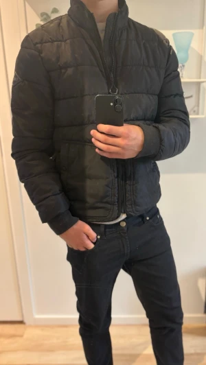  Replay pufferjacka  - Säljer en svart pufferjacka från Replay med hög krage och dragkedja framtill. Jackan har två stora fickor med knappstängning och quiltad design. Perfekt för kalla vinterdagar och riktigt skön att bära. Håller värmen otroligt bra🙌