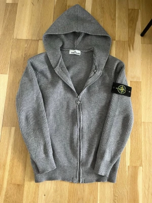 Grå stickad hoodie från Stone Island - Säljer en grå stickad hoodie från Stone Island som är ribbstickad. Säljer pga den är för liten för mig. Skulle säga att den sitter som S. 