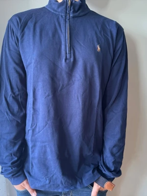 Polo ralph lauren Marinblå långärmad tröja med halvzip - Snygg marinblå långärmad tröja från Polo Ralph Lauren med halvzip och liten broderad logga på bröstet. Tillverkad i mjukt bomullsmaterial och har en hög krage. Perfekt för en avslappnad men stilren look. Änvänd 3 gånger. Den är xl för barn, jag är 170 och den passar relativt bra på mig, pris kan diskuteras