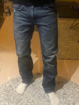 Mörkblå raka jeans herr - Säljer ett par mörkblå jeans med raka ben och klassisk femficksmodell. Jeansen har subtila slitningar och kontrastsömmar. Passar perfekt till en avslappnad stil och är tillverkade i denim med snygg tvätt.