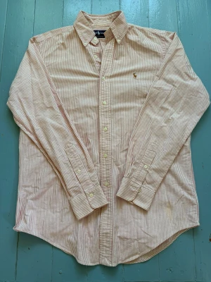 Ralph lauren skjorta  - Ass fett Ralph lauren skjorta! Köpt i usa så den är i deras storlek men motsvarar M ungefär! Ny pris 2299kr! Vårt pris endast 399kr! Rosa randig vilket är väldigt eftersökt så passa på! Mycket fint skick förutom en liten fläck som säkert går bort i tvätten! 