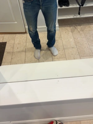 Blå slim jeans med slitningar - Säljer ett par blå replay grover jeans med smal passform och slitningar på låren. Jeansen har klassisk femficksdesign och normal midja. 