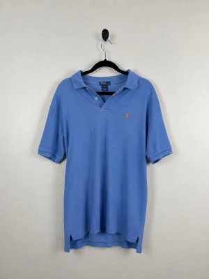 Vintage Polo Ralph Lauren Piké L 16/18 Ljusblå 100% Bomull Orange Pony Y2K PreppyVintage Polo Ralph Lauren Piké L 16/18 Ljusblå 100% Bomull Orange Pony Y2K Preppy - • Storlek: L 16/18 • Färg: Ljusblå • Passform: Regular Fit  • Krage: Klassisk pikékrage • Material: 100% bomull  Skick: Plagget är i väldigt fint skick med ett mindre hål vid ena armen och en fläck på nederdelen. Eventuella anmärkningar anges alltid tydligt i beskrivningen och visas på bilderna.  Nypris: Cirka 1 500 kr.  📦 Skickas snabbt och packas omsorgsfullt. 💬 Hör gärna av dig om du har frågor eller vill se fler bilder. 🤝 Samfrakt erbjuds vid köp av flera plagg – kika gärna in mina andra ann