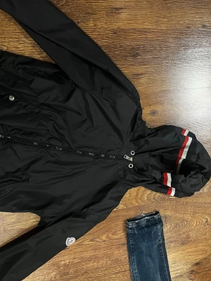 Svart moncler vind breacker jacka - Svart moncler vind breacker jacka saknar knapp o på ena fickan