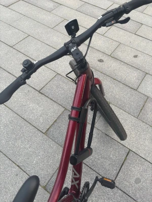 Vinröd cykel med AXA-lås - Säljer en vinröd cykel med svart styre och sadel. Cykeln har ett AXA-lås monterat på ramen, reflexer på hjulen och breda däck. Perfekt för dig som vill ha en smidig och snygg cykel för stan eller längre turer. Väldigt bra skick. 