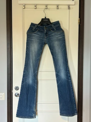 Blå bootcut jeans från Lee - Säljer ett par klassiska blå lågmidjade bootcut jeans från Lee i stl 25-33.  Midjemått: 34cm Innerbenslängd: 81cm Defekter jag kunnat se:Hål i fickans innerfoder (ej i själva jeansen) samt viss missfärgning och slitage vid bensluten. Se bild 5-6. 