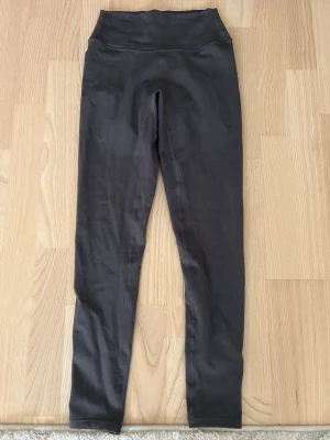 Svarta scrunch tights från MKlifestyle - Säljer ett par svarta scrunch tights från MKlifestyle med hög midja och tight passform. Materialet är stretchigt och mjukt, perfekt för gymmet eller yoga. Diskret logga bak och scrunch-söm som framhäver formen. Använda endast 1 gång.