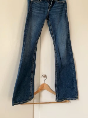 Blå bootcut jeans från Gina Tricot - Säljer ett par blå bootcut jeans från Gina Tricot i storlek 164. Jeansen har klassisk femficksmodell, dragkedja och knapp framtill samt kontrastsömmar. Materialet är denim i bomull med lätt stretch. Perfekta för en avslappnad och trendig look.