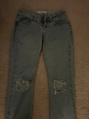 Junkyard jeans - Jättefina ljusblå jeans med hål vid knäna. Väldigt bra skick men lite söndertrampade längst ner vid fötterna men inget som syns. Hittade ingen bättre bild med byxorna på!