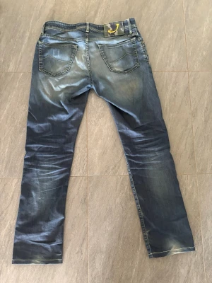 Blå jeans från Jacob Cohën  - Snygga blå med tvättade detaljer. Jeansen har två bakfickor och klassisk femficksdesign. Materialet är denim med en något stretchig känsla för extra komfort. Perfekta för en avslappnad och trendig look. Skriv gärna vid frågor och funderingar, priset är ej hugget i sten 😊