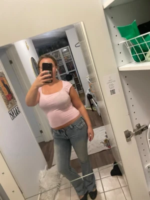 Ljusrosa croppad topp - Säljer en ljusrosa croppad topp med rund halsringning och korta ärmar. Toppen är figurnära och har en enkel, stilren design som passar perfekt till jeans eller kjol. Materialet känns mjukt och stretchigt, troligen bomull eller en bomullsblandning.
