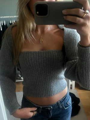 Grått stickat sett med offshoulder topp och kofta - Trendig grå stickad croppad topp med en matchande stickad kofta. Perfekt för dig som vill ha en modern och stilren look.