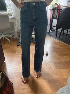 Blå raka high waist jeans - Säljer ett par klassiska blå jeans med hög midja och raka ben. Jeansen har fem fickor, bälteshällor och stängs med knapp och dragkedja. Perfekta till vardagslooken och passar till det mesta. Materialet är kraftig denim i bomull.