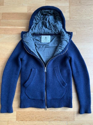 Marinblå Boggi Milano hoodie/cardigan i merinoull - Svinsnygg marinblå hoodie/cardigan med huva från Boggi Milano. Tröjan är i 100% merinoull och är i väldigt fint skick. Det står att den är i storlek S men har krympt i tvätten och sitter som Xxs. Den har en slimmad passform. Nypris ca 3000kr. Vid frågor eller funderingar är det bara att höra av sig. Pris kan diskuteras! 