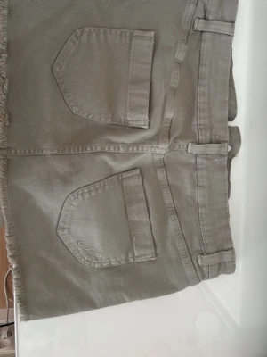 Grön jeanskjol med fransad kant - Snygg grön jeanskjol med fransad nederkant och stora fickor både fram och bak. Mjuk och skönt material och i ett jättebra skick, endast använd en gång.