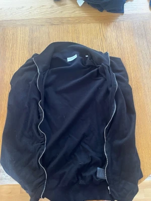 Svart ziptröja från Lindbergh - Stilren svart ziptröja från Lindbergh i slim fit-modell. Tröjan har dragkedja framtill och är tillverkad i mjukt material.