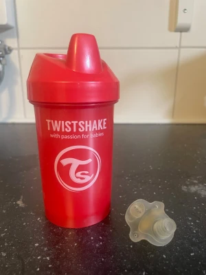 Röd Twistshake pipmugg för barn - Säljer en röd pipmugg från Twistshake med vitt tryck och tillhörande silikonventil. Muggen är tillverkad i plast och har ett praktiskt lock med pip, perfekt för små barn. Enkel att ta isär och rengöra. Passar bra för både vatten och juice.