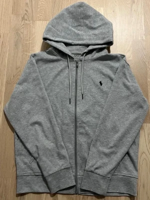 Grå zip hoodie från Polo Ralph Lauren - Säljer en zip hoodie från Polo Ralph Lauren. Den är i bra skick o inte använd så mycket. Storlek S men skulle säga M. Tveka inte på att höra av dig vid frågor eller funderingar!