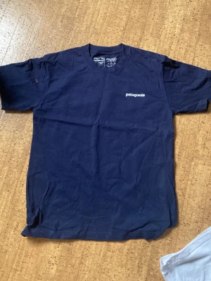 Mörkblå Patagonia t-shirt i bomull - Snygg mörkblå t-shirt från Patagonia med regular fit och diskret logga på bröstet. Tillverkad i mjuk bomullsmix som känns skön mot huden. Perfekt till jeans eller shorts för en avslappnad look.