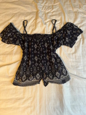Mörkblå offshoulder topp med mönster - Snygg mörkblå offshoulder topp med vitt mönster. Storlek XS