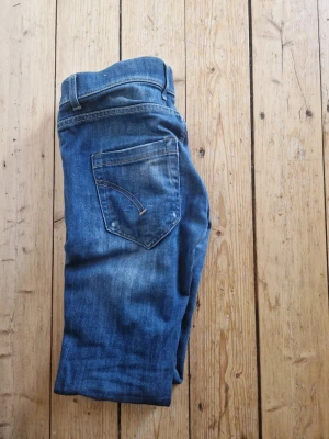 Blå raka jeans med slitningar - Säljer ett par klassiska blå jeans i rak modell med snygga slitningar och tvättade detaljer. Jeansen har fem fickor, normal midja och är gjorda i denim. Perfekta för en avslappnad och trendig look.