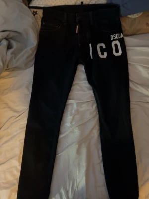 Svarta dsquared2 jeans - Säljer ett par sköna svarta jeans från Dsquared2 med vit text 'ICON' på framsidan och med röd lap vid gylfen. Köpte dem för ca 4000kr och har använt dom lite men dom ser fortfarande bra ut😁säljer dom nu för dom passar tyvärr inte mig längre. Om ni har några frågar så är de bara att skriva🫡🫡