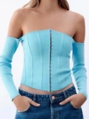 Ljusblå off shoulder korsett - Ljusblå korsett med off shoulder-långa ärmar och knäppning framtill. Figurnära passform och lätt v-formad nederkant ger en snygg siluett. Storlek S, aldrig använd🩷