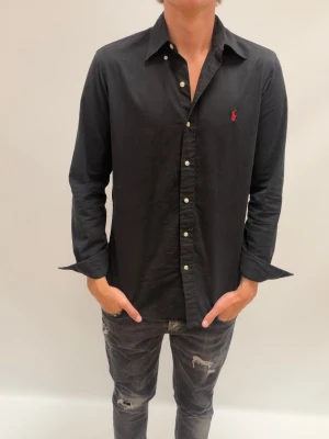 Ralph Lauren skjorta  - Snygg svart Raffe skjorta köpt i Kungsbacka för 1 år sedan ruggit goe och ha på fester nu till hösten/ vintern. Är 190 lång och väger 75 kg 