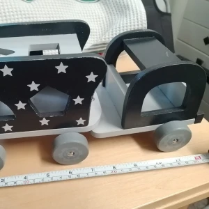 Svart och vit träleksak med stjärnor - Unik handgjord träleksak i svart och vitt med hjul och utskurna former. Ena sidan är dekorerad med vita stjärnor och olika geometriska hål. Perfekt som inredningsdetalj eller leksak till barnrummet.