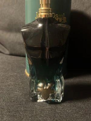 Jean Paul Gaultier Le Male parfym - Ikonisk parfymflaska formad som en manlig torso i mörkblått och silver. Flaskan har en metallisk kork och detaljerad design, vilket gör den till en klassiker på parfymhyllan. Passar dig som gillar stilrena och unika doftflaskor.