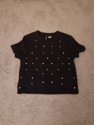 Tshirt med pärlor - Svart tshirt med vita pärlor på. Den är i ett lite tjockare matrial.🌸🩷